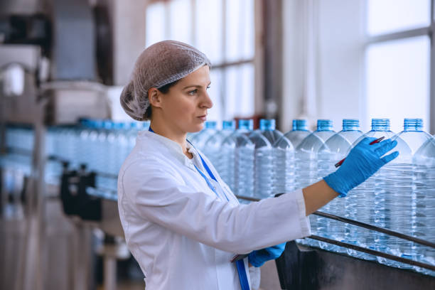 istock Technologist in bottling factory checking water bottles before shipment. 1355620466