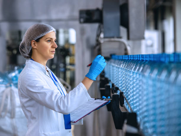 istock Technologist in bottling factory checking water bottles before shipment. 1355621521