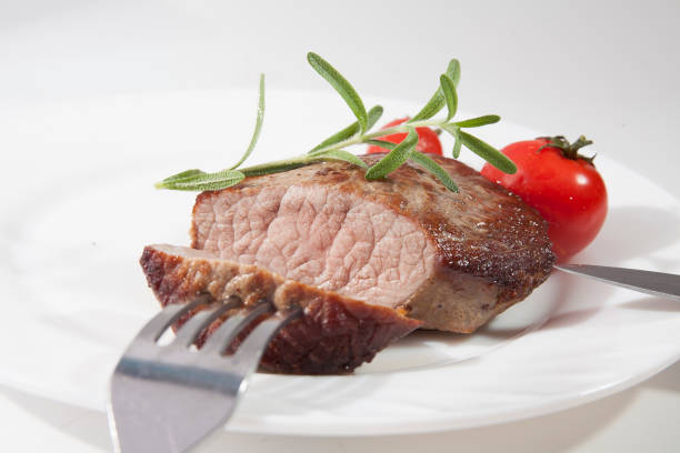 Appetizing steak well done on a white plate with tomatoes and rosemary