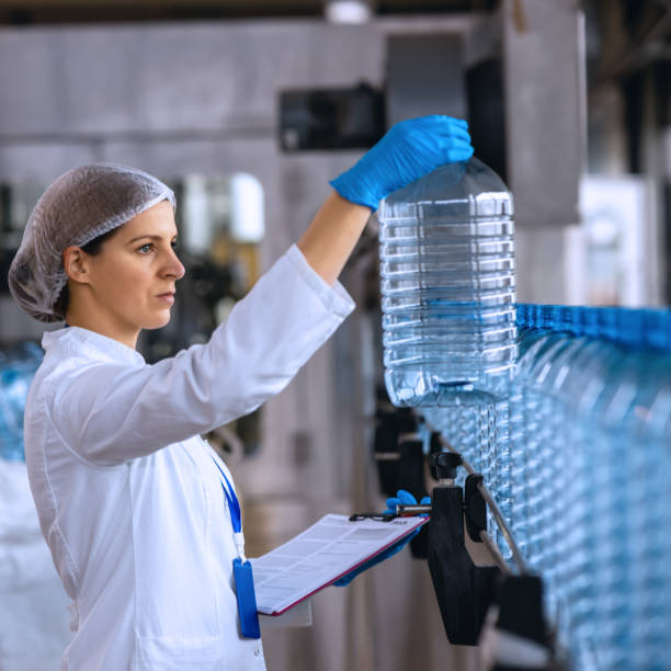 istock Technologist in bottling factory checking water bottles before shipment. 1355621974