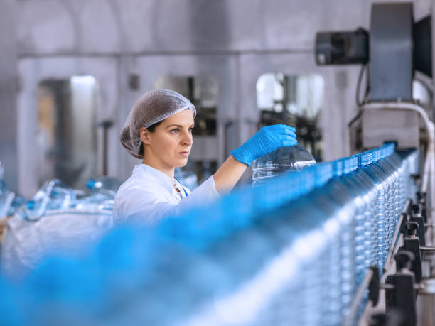 Technologist in bottling factory checking water bottles before shipment.