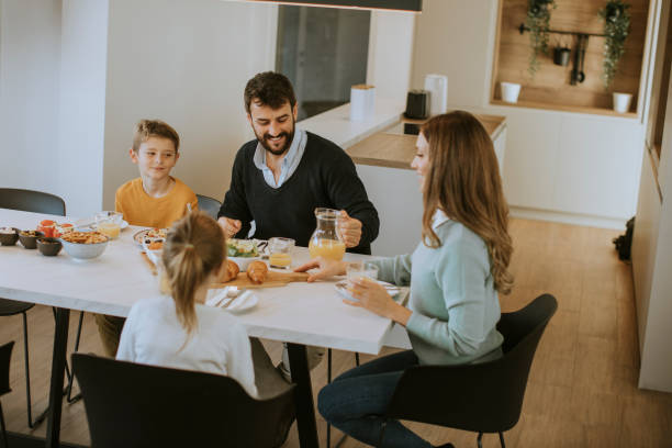 istock Young happy family talking while having breakfast at dining table 1355624233