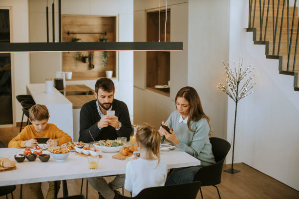 istock Family using mobile phones while having breakfast at dining table at apartment 1355624245