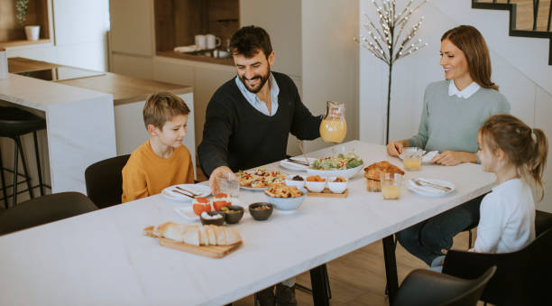 istock Young happy family talking while having breakfast at dining table 1355624266
