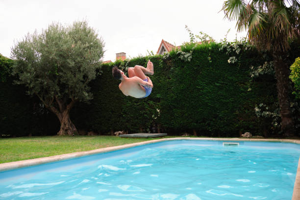 istock Young caucasian man jumping into the swimming pool. 1355625540