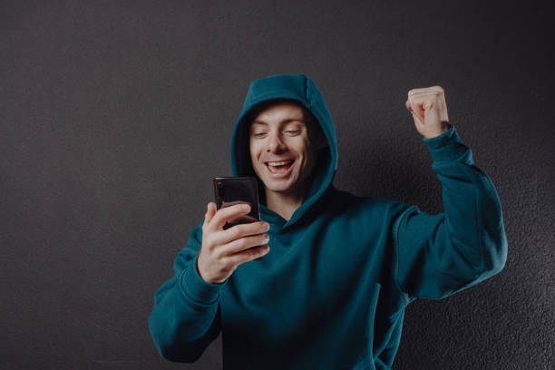 istock Happy man in hoodie using smartphone 1355626431