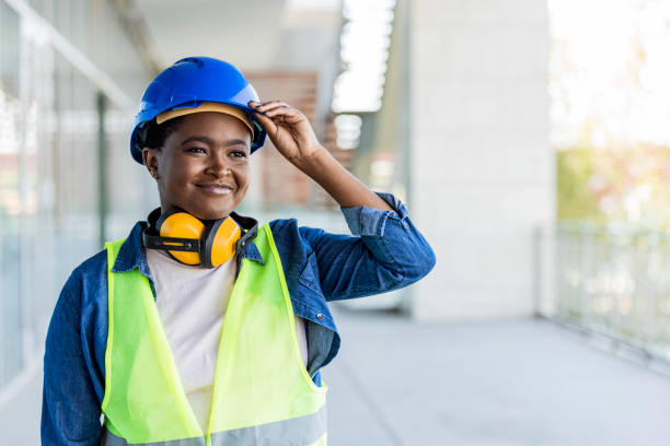 Portrait of woman engineer at building site looking at camera with copy space. Portrait of woman engineer at building site looking at camera with copy space. Construction manager standing in yellow safety vest and blue hardhat. Successful confident architect at construction site. safe security equipment stock pictures, royalty-free photos & images