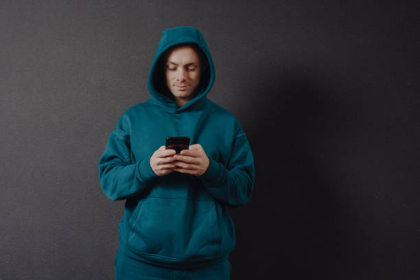 istock Man in hoodie using smartphone 1355626777