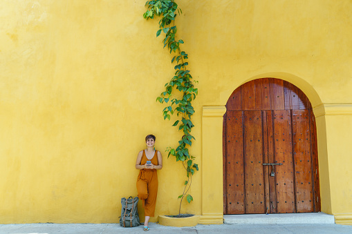 Horizontal view of latin american woman in front of yellow building. People and colors concept.