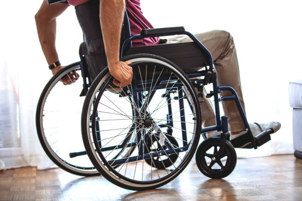 istock Disabled Person Sits in Wheelchair Against Window. 1355632553