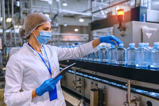 istock Technologist in bottling factory checking water bottles before shipment. 1355632586