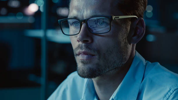 istock At Night Portrait of Handsome Startup Digital Entrepreneur Working on Computer, Line of Code Reflecting in Glasses. Developer Working on Innovative e-Commerce App using AI Algorithm Big Data. Blue 1355632591