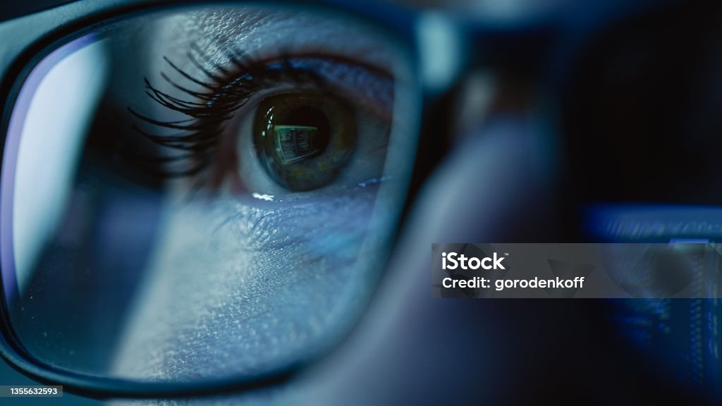 Super Close-up on Female Eye, Software Engineer Working on Computer, Programming Reflecting in Glasses. Developer Working on Innovative e-Commerce Application using Machine Learning, AI, Big Data Surveillance Stock Photo
