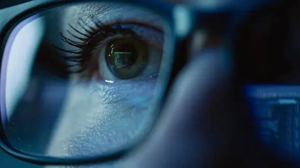 Photo of Super Close-up on Female Eye, Software Engineer Working on Computer, Programming Reflecting in Glasses. Developer Working on Innovative e-Commerce Application using Machine Learning, AI, Big Data