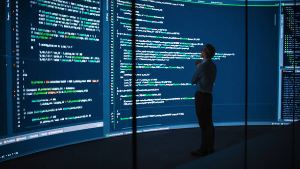 High-Tech Startup Concept: Innovative Male Software Engineer Standing, Doing Big Data Analysis on Wall Screen Showing Porgramming Code. Developing Futuristic e-Commerce App with Machine Learning. concepto de startup de alta tecnología: ingeniero de software masculino innovador de pie, haciendo análisis de big data en la pantalla de la pared que muestra el código de porgramming. desarrollo de aplicaciones futuristas de comercio electrónico con a