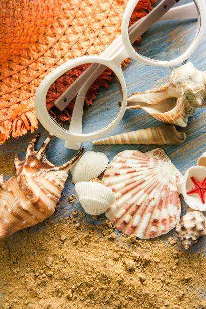 istock beach accessories glasses hat cockleshells on wood deck. 1355634143