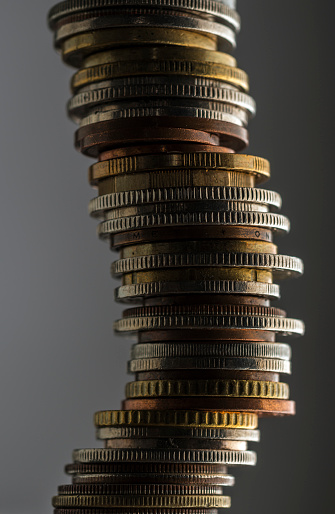 Large stack of international coins against a grey background.