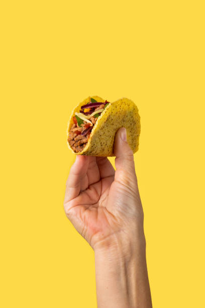 mano sosteniendo un taco mexicano - taco alimento fotografías e imágenes de stock