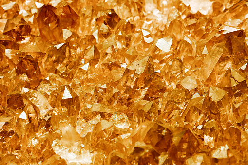 Cluster of golden quartz mineral crystals (chemical composition SiO2) close up background texture, high angle view