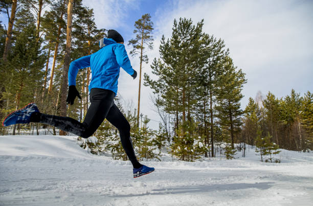 istock male runner running on snowy trail in winter forest 1355641942