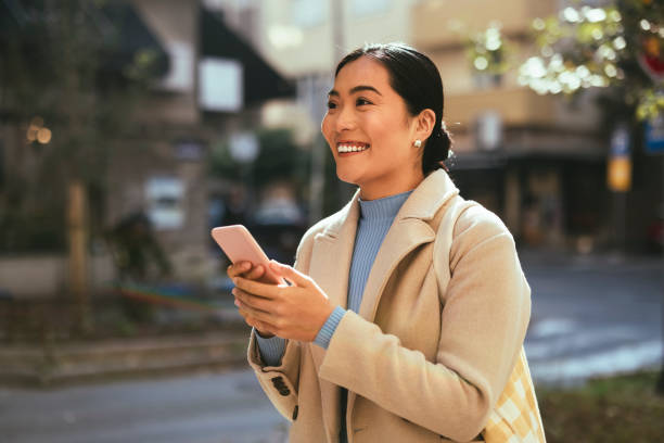 istock Beautiful Woman Using Mobile Phone Outdoors 1355642271