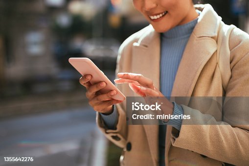 istock Close Up Photo of Woman Hands Using Mobile Phone Outdoors 1355642276