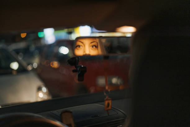 istock Young beautiful female driver looking at herself in rearview mirror 1355642382