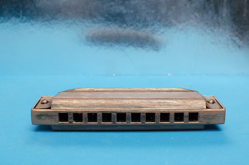 Old harmonica on a blue background.Musical instrument.