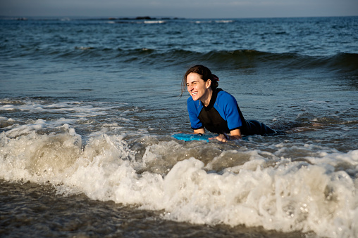Woman swimming in the ocean with bodyboard.