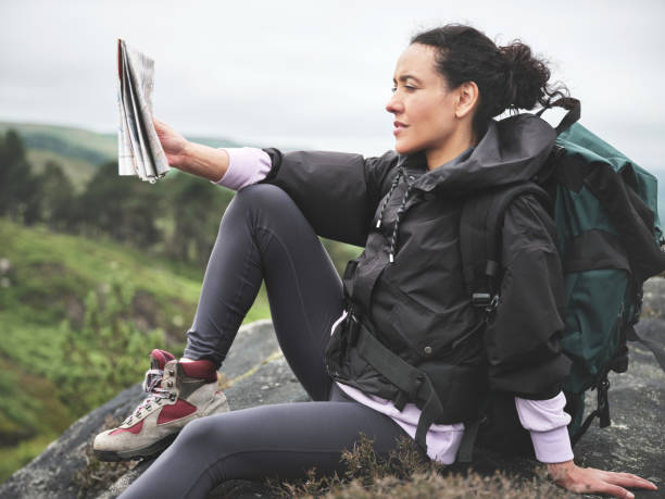 foto de una atractiva joven sentada en una roca y luciendo contemplativa mientras lee un mapa durante una caminata - map uk hiking reading fotografías e imágenes de stock