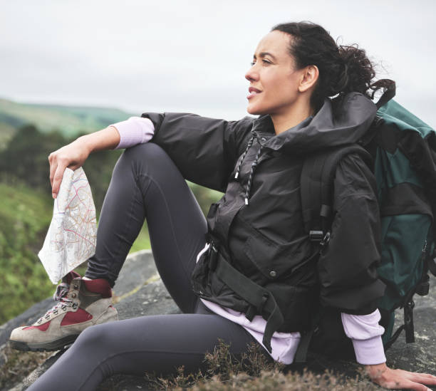 foto de una atractiva joven sentada en una roca y luciendo contemplativa mientras sostiene un mapa durante una caminata - map uk hiking reading fotografías e imágenes de stock