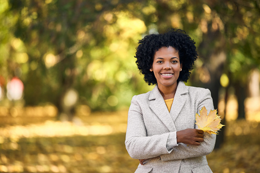 Portrait of happy african-american woman, holding a leaf.