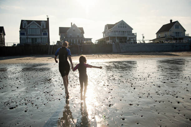 Mother and daughter running on the beach at sunset.