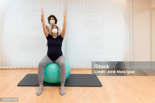 Physiotherapist Helping To Stretch The Arms Of A Pregnant Woman To Exercise Sitting On A Fitness Ball Stock Photo - Download Image Now