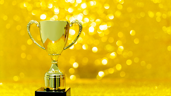 Golden winner's cup placed on wooden table in football stadium.