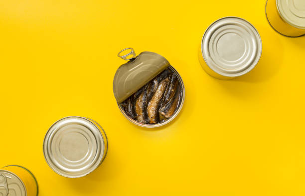 Small opened can of sardines resting on a vibrant blue plate, displayed on a rustic wooden table, inviting a delicious meal experience