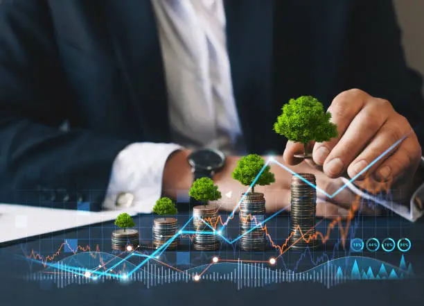 Eco business investment. Green business growth. Businessman holding coin with tree growing on money coin stack. Finance sustainable development.Concept of pass and increase of renewable energy