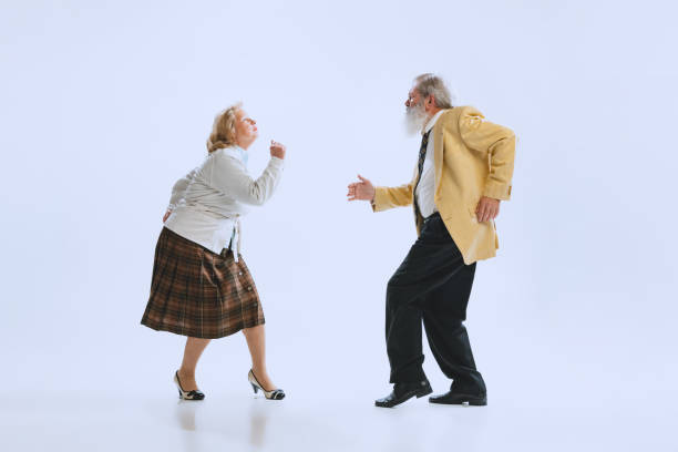 portrait dynamique de danseurs de style rétro, homme et femme âgés en tenue vintage dansant swing isolé sur fond blanc - senior couple isolated couple senior adult photos et images de collection