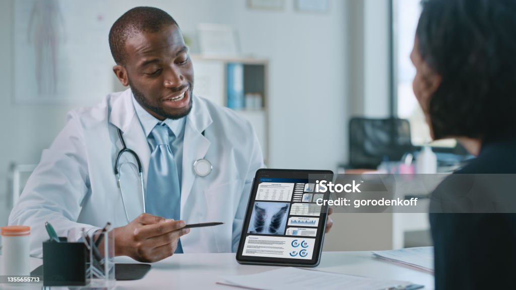Doctor Consultation Office: Female Patient Listens to Experienced Pulmonologist Uses Digital Tablet Computer to Show, Explain Lung Analysis Results, Give Advice, Prescribe High-Pressure Medicine Lung Cancer Stock Photo