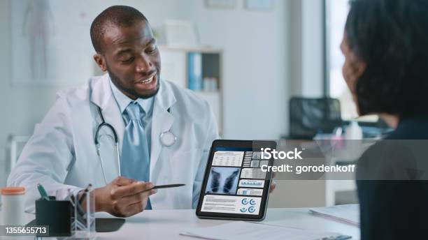 Doctor Consultation Office Female Patient Listens To Experienced Pulmonologist Uses Digital Tablet Computer To Show Explain Lung Analysis Results Give Advice Prescribe Highpressure Medicine Stock Photo - Download Image Now