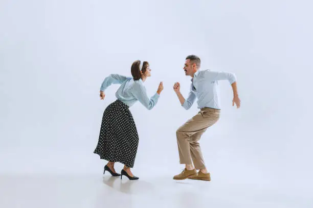 Photo of Two dancers, young man and woman in old-school fashioned attire dancing rock-and-roll isolated on white background