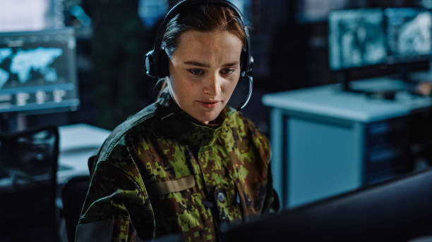 サイバーセキュリティ、技術、陸軍通信の管理のための中央オフィスハブで働くヘッドセットの美しい女性軍事監視官、 - military technology ストックフォトと画像