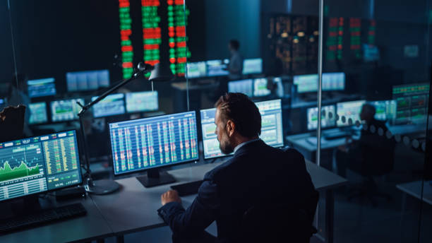 istock Professional Financial Data Analysts Working in a Modern Monitoring Office with Live Analytics Feed on a Big Digital Screen. Monitoring Room with Finance Specialists Sit in Front of Computers. 1355656558