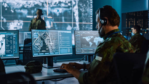 Military Surveillance Officer Working on a City Tracking Operation in a Central Office Hub for Cyber Control and Monitoring for Managing National Security, Technology and Army Communications. Military Surveillance Officer Working on a City Tracking Operation in a Central Office Hub for Cyber Control and Monitoring for Managing National Security, Technology and Army Communications. watching stock pictures, royalty-free photos & images