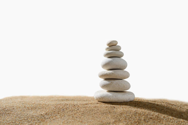 Tower of white pebbles on the sand on a white background. Isolated object.