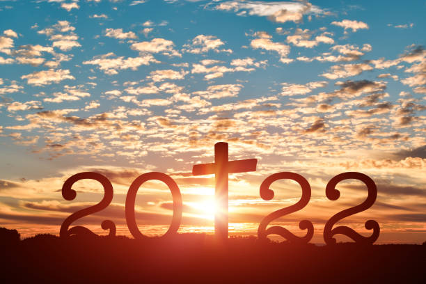 Silhouette of Christian cross with 2022 years at sunset background. stock photo