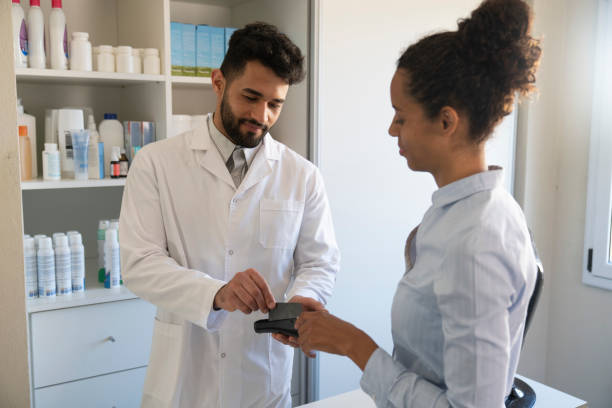 istock Latin pharmacist swiping credit card in reader at pharmacy 1355658816