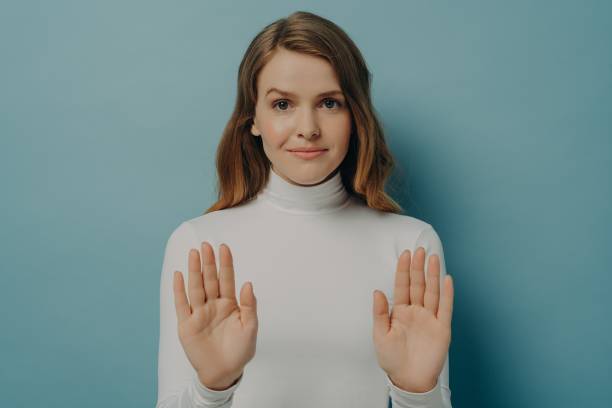 istock Attractive young focused woman showing stop gesture, saying no, isolated over blue studio background 1355661735