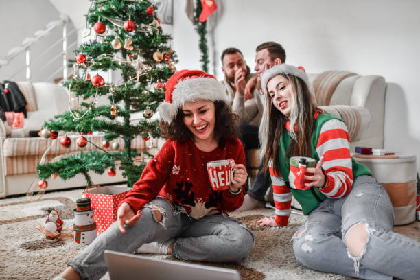 Smiling Females Enjoying TV Show On Laptop And Annoying Boyfriends During Christmas Party Smiling Females Enjoying TV Show On Laptop And Annoying Boyfriends During Christmas Party cross match stock pictures, royalty-free photos & images