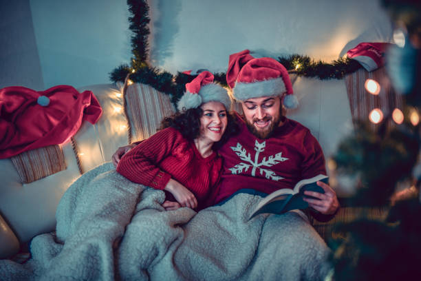 istock Couple Enjoying Christmas Eve Together By Reading Book Under Blankets 1355663176
